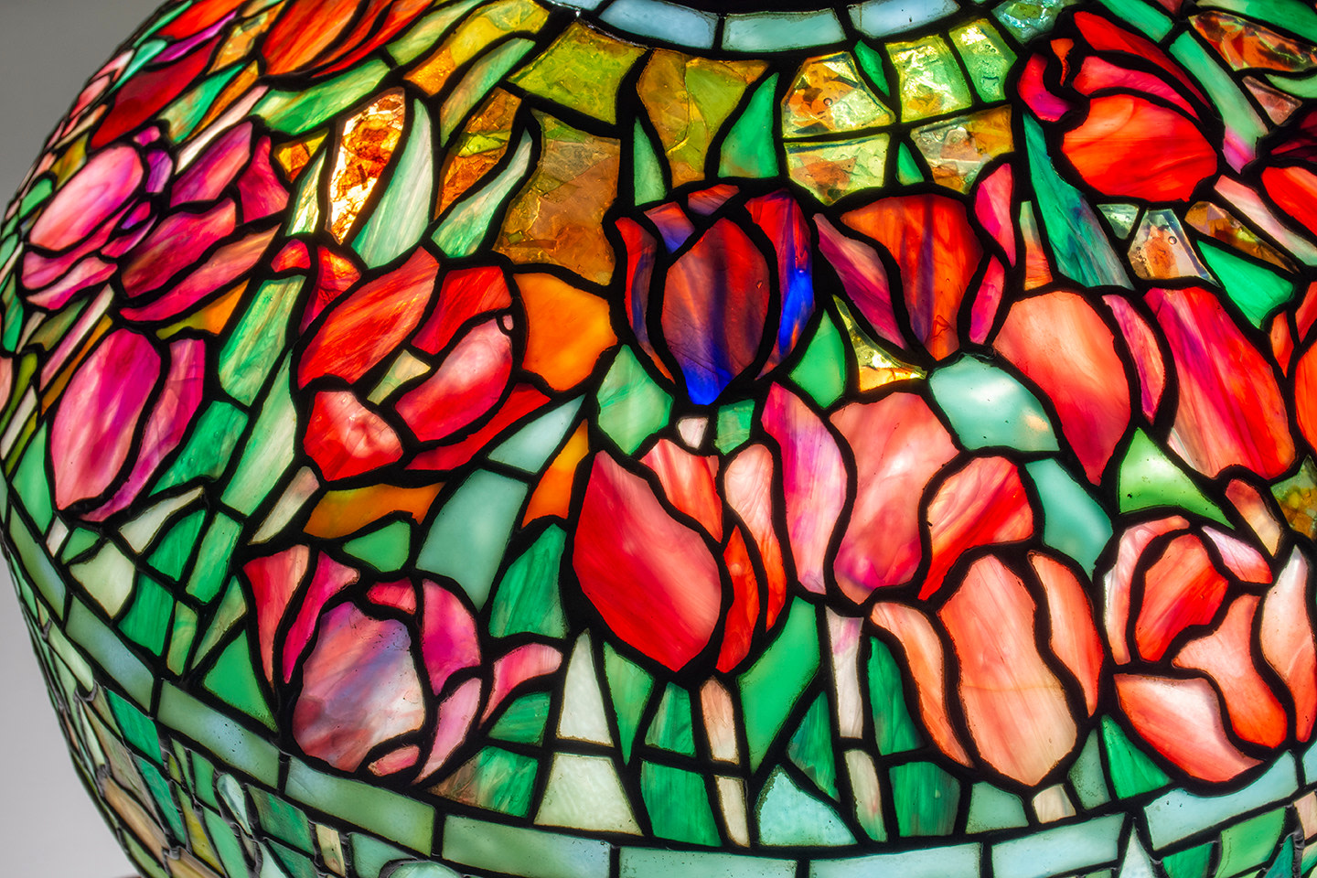 a leaded glass tiffany lamp shade depicting red and pink tulips in variegated glass