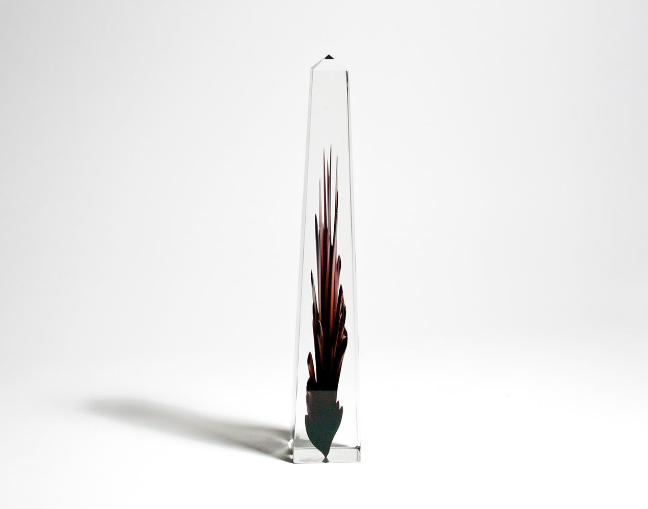 An obelisk of clear glass, the lower portion with an encased flame-like motif in deep purple glass with black streaks