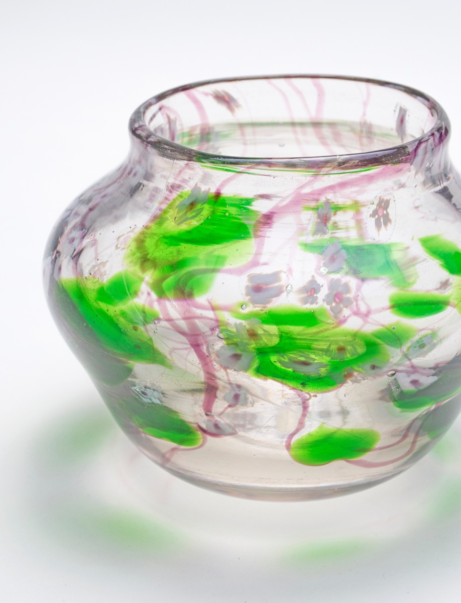 a detail shot showing a tiffany favrile glass paperweight vase, showing detail of the glasswork decoration of favrile glass flowers, leaves and vines