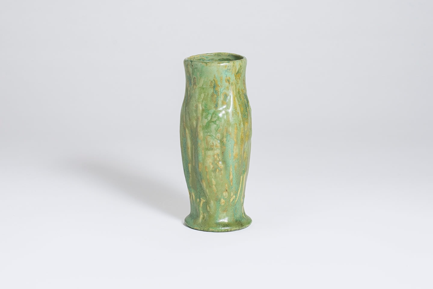 a cabinet vase with variegated green-yellow glaze, of cylindrical form with slight bulge at the center, with indistinct naturalistic relief decoration depicting a milkweed pod with seeds
