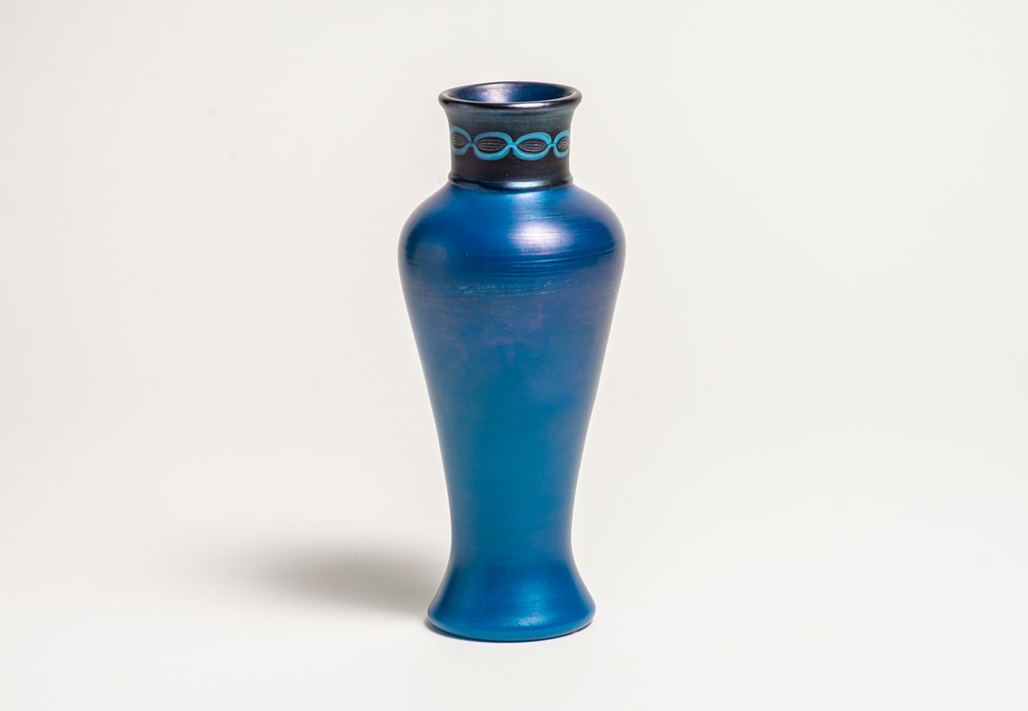 a baluster form Tiffany Glass vase, the body in deep iridescent blue, the straight neck in a silvery black iridescent glass decorated with chain link design inspired by ancient vases