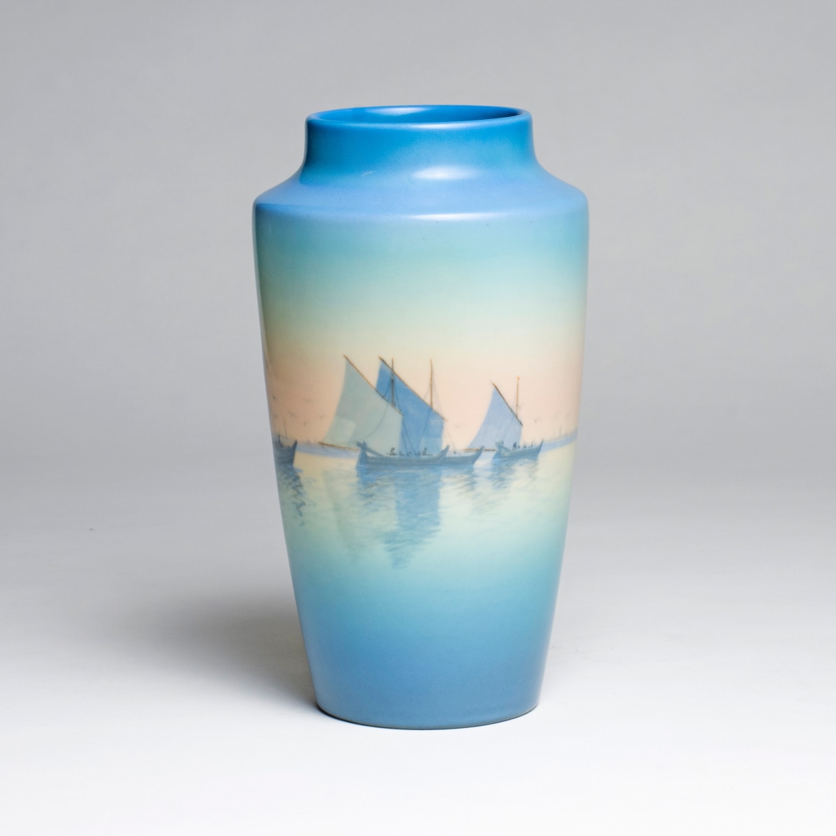 a glazed ceramic vase by carl schmidt for rookwood pottery in the scenic vellum glaze depicting a harbor scattered with ships with gradient sky
