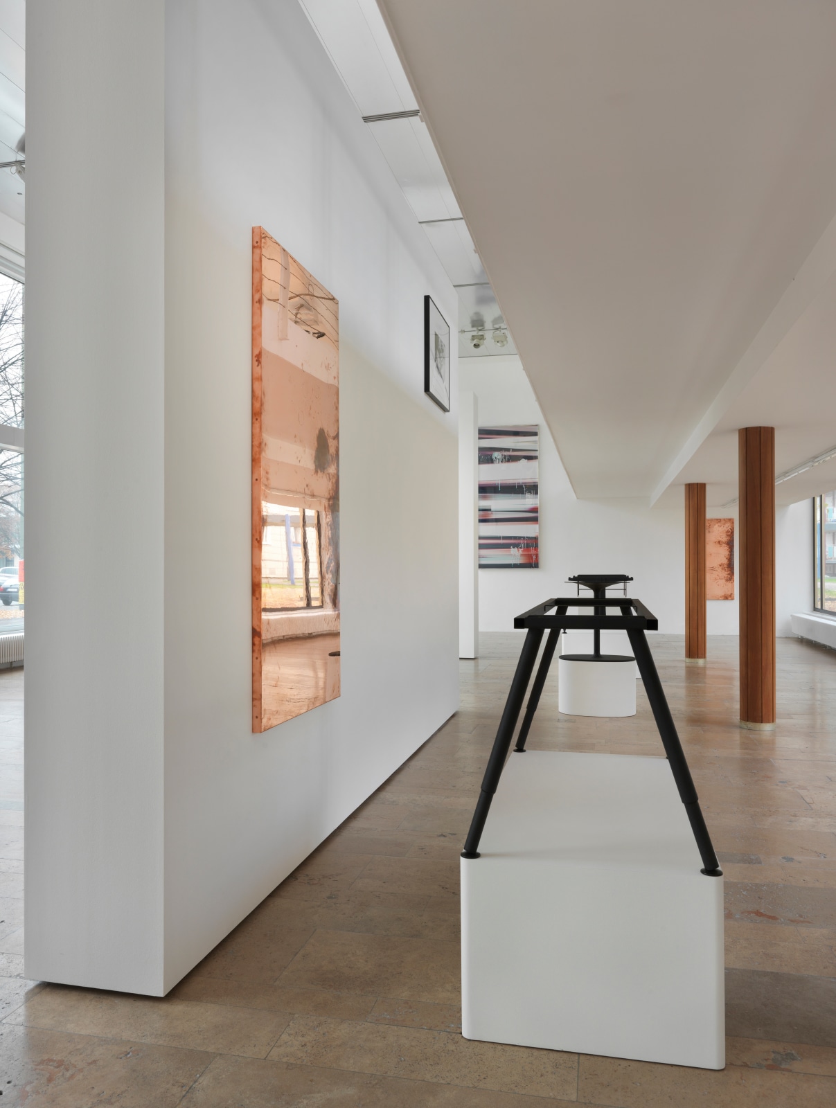 Installation view from Beshty's show at Capitain Petzel with a copper desktop surrogate on the left wall, a desk skeleton on a pedestal in front of the surrogate, and multicolored curl hanging on the back wall.