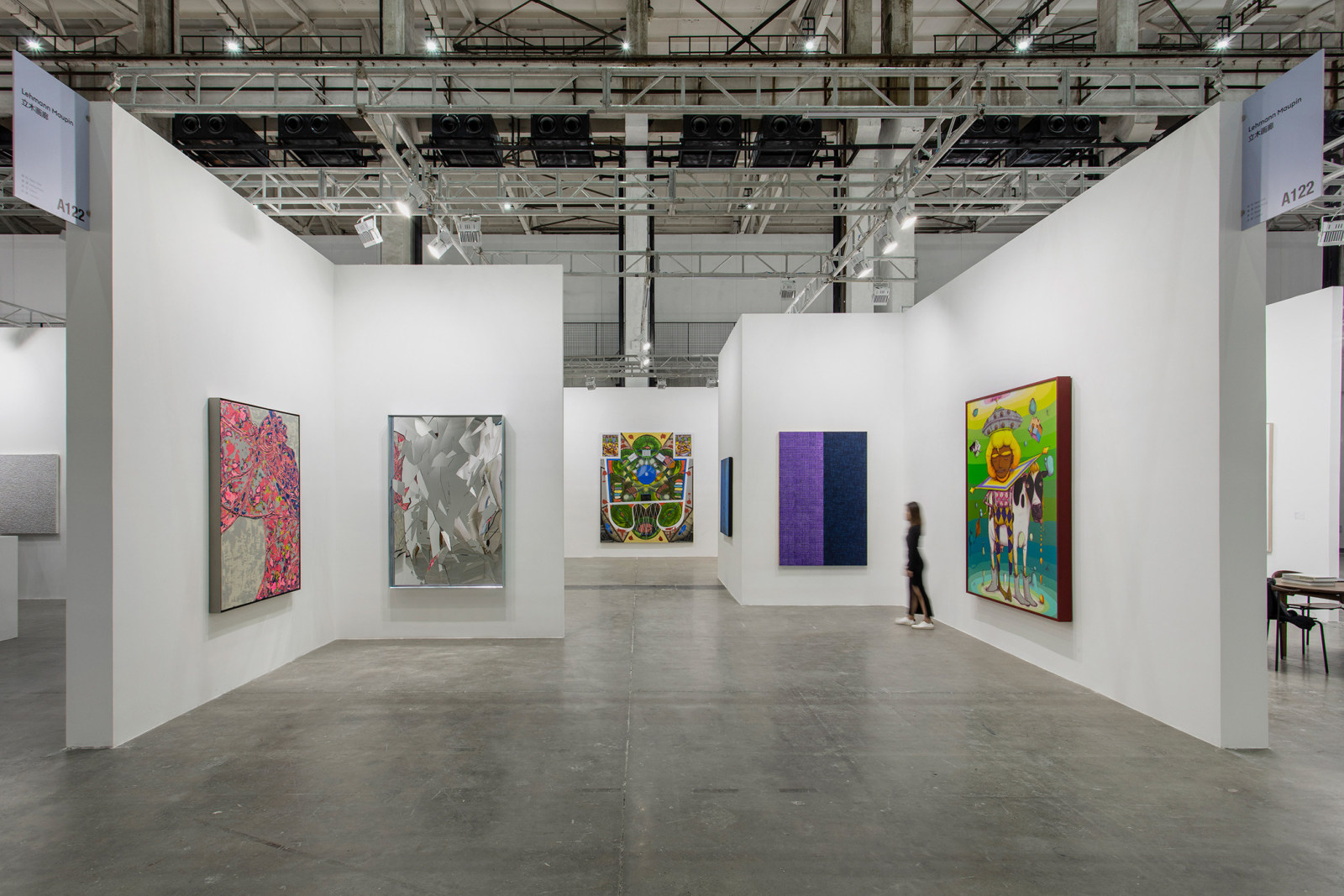 First installation view of Lehmann Maupin's booth at West Bund Art &amp; Design 2020 showing five paintings and one mirrored sculpture hanging on the wall. One person is walking through the booth.