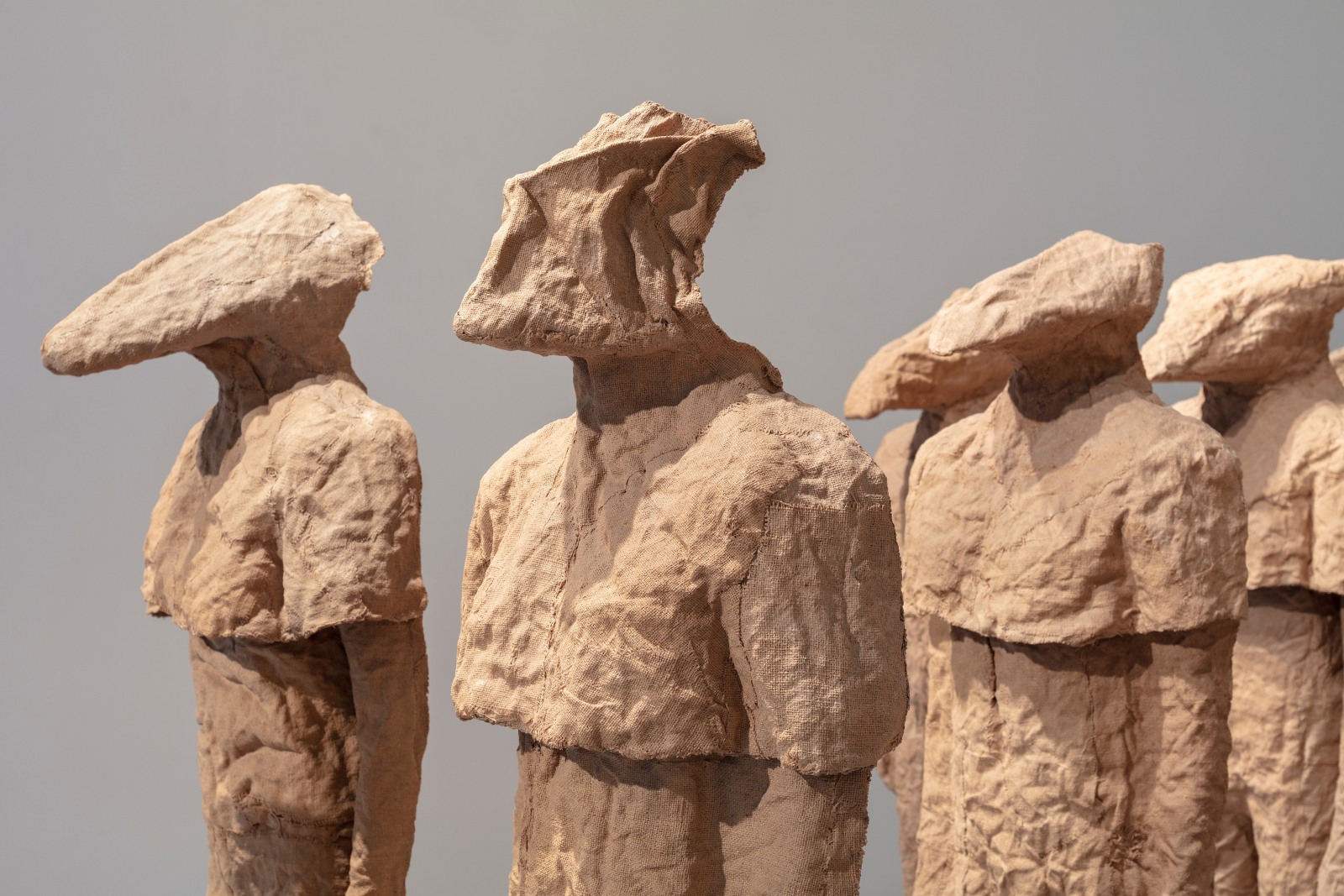 Detail view of multiple burlap and resin figures with different heads by Magdalena Abakanowicz