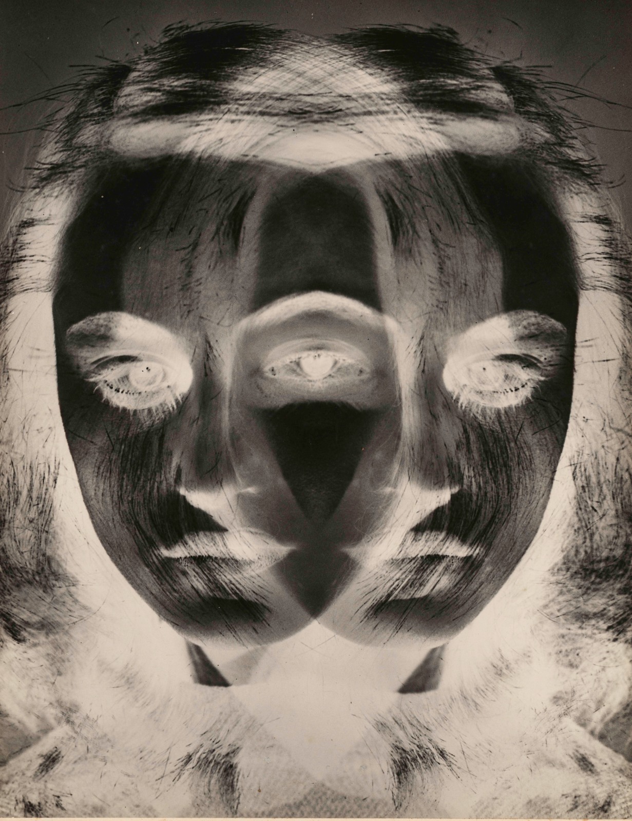 A black and white inverted image shows a young woman's face exposed twice and overlapping itself.