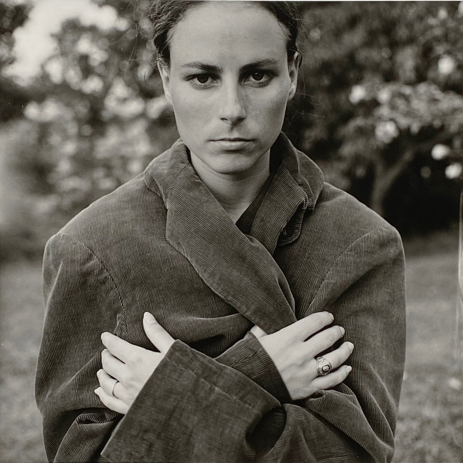 A woman gazes at the camera with a serious expression, while wearing an oversized coat in this black and white photo.