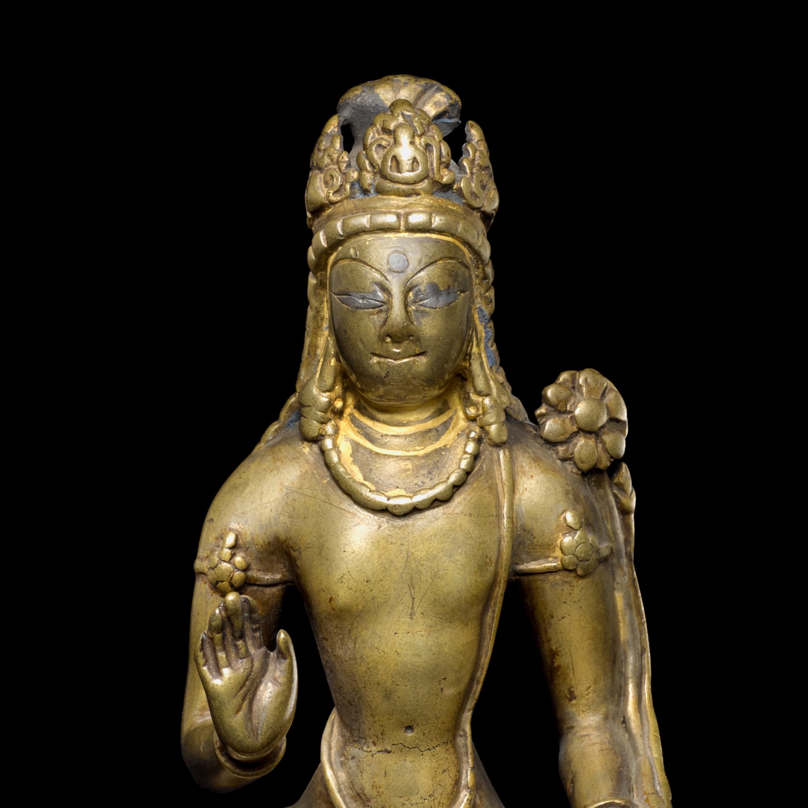 Detail of an elegant sculpture of Avalokiteshvara Padmapani seated at ease with his left leg reaching over his pedestal 
