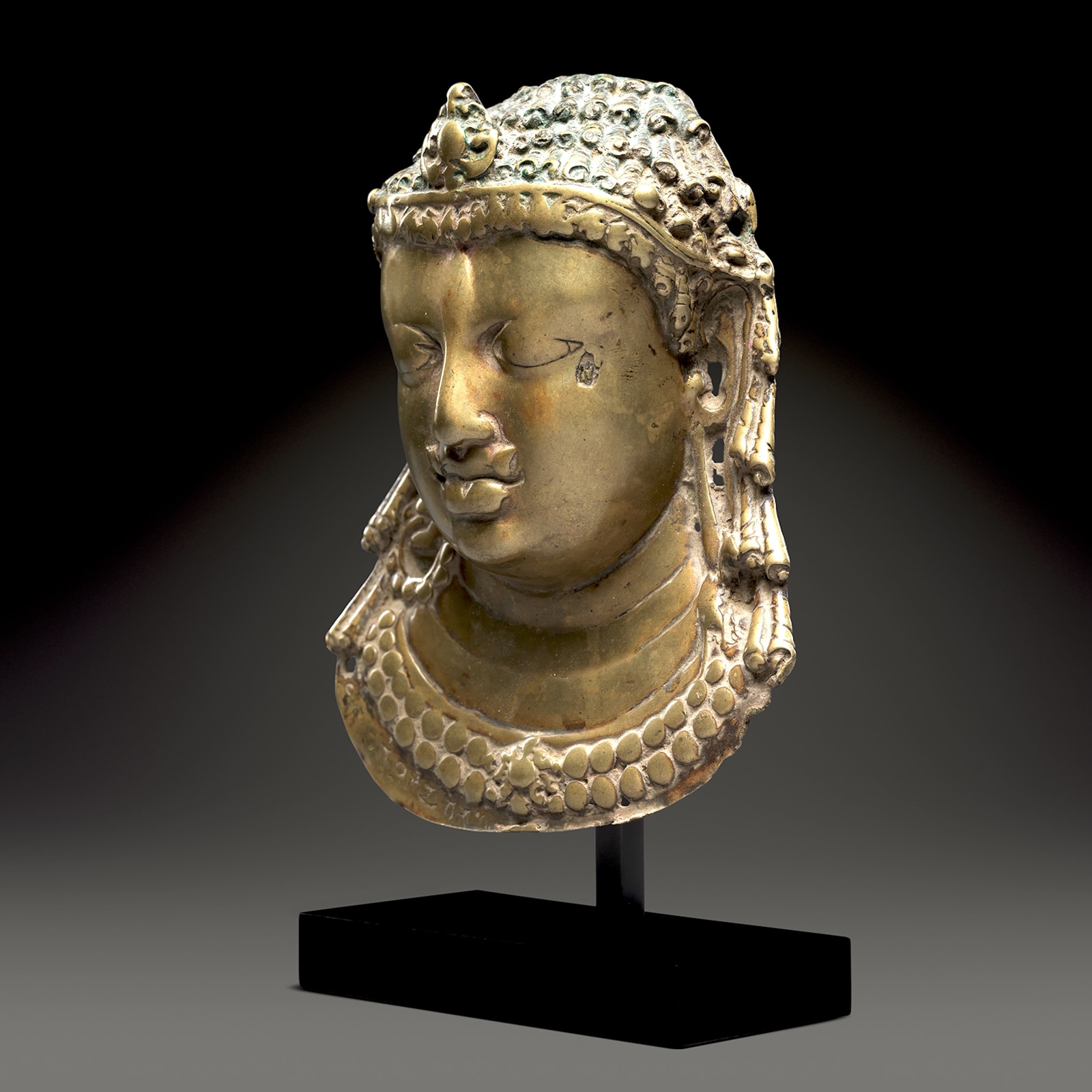 This brass relief represents the Hindu god Shiva, the facial features worn by the repeated use of ritual unguents