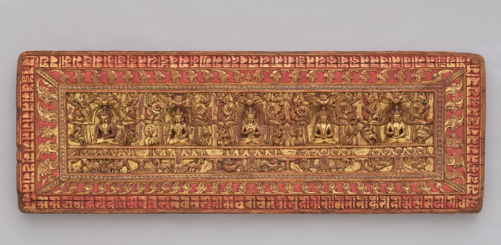 The wood panel is deeply carved on the interior side with the five Tathagatas—Vairocana at the center flanked by Amitabha and Akshobhya, with Amoghasiddhi and Ratnasambhava at either end.