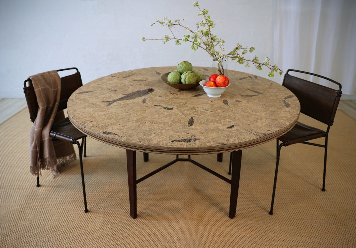 A 60&quot; round fossil stone table on a hand-forged iron base. The table top was cut from our &quot;Fossil Storm&quot; stone layer. The fossils include a large 17&quot; Diplomystus dentatus, and 22- Knightia eocaena. The fossils date to the Early Eocene, 50 million years old. The top has been sealed and protected with two factory coatings of a silicone-based sealer designed to protect it against stains. The base is an artisan hand-forged base that stands 28-1/2&quot; tall, made exclusively for our fossil stone. Overall size: 60&quot; wide x 30-1/2&quot; tall.