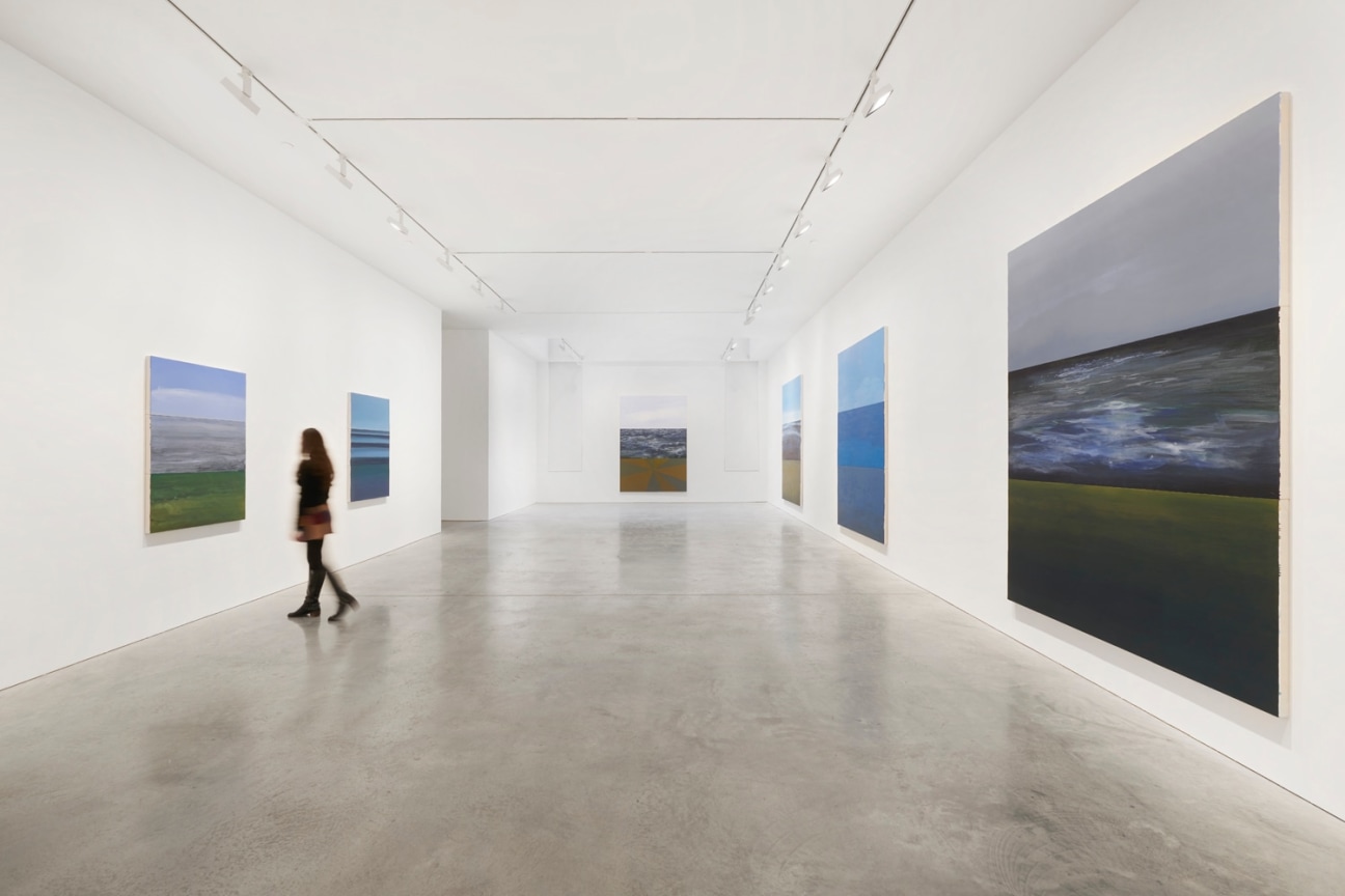 person walking through the long gallery with several paintings