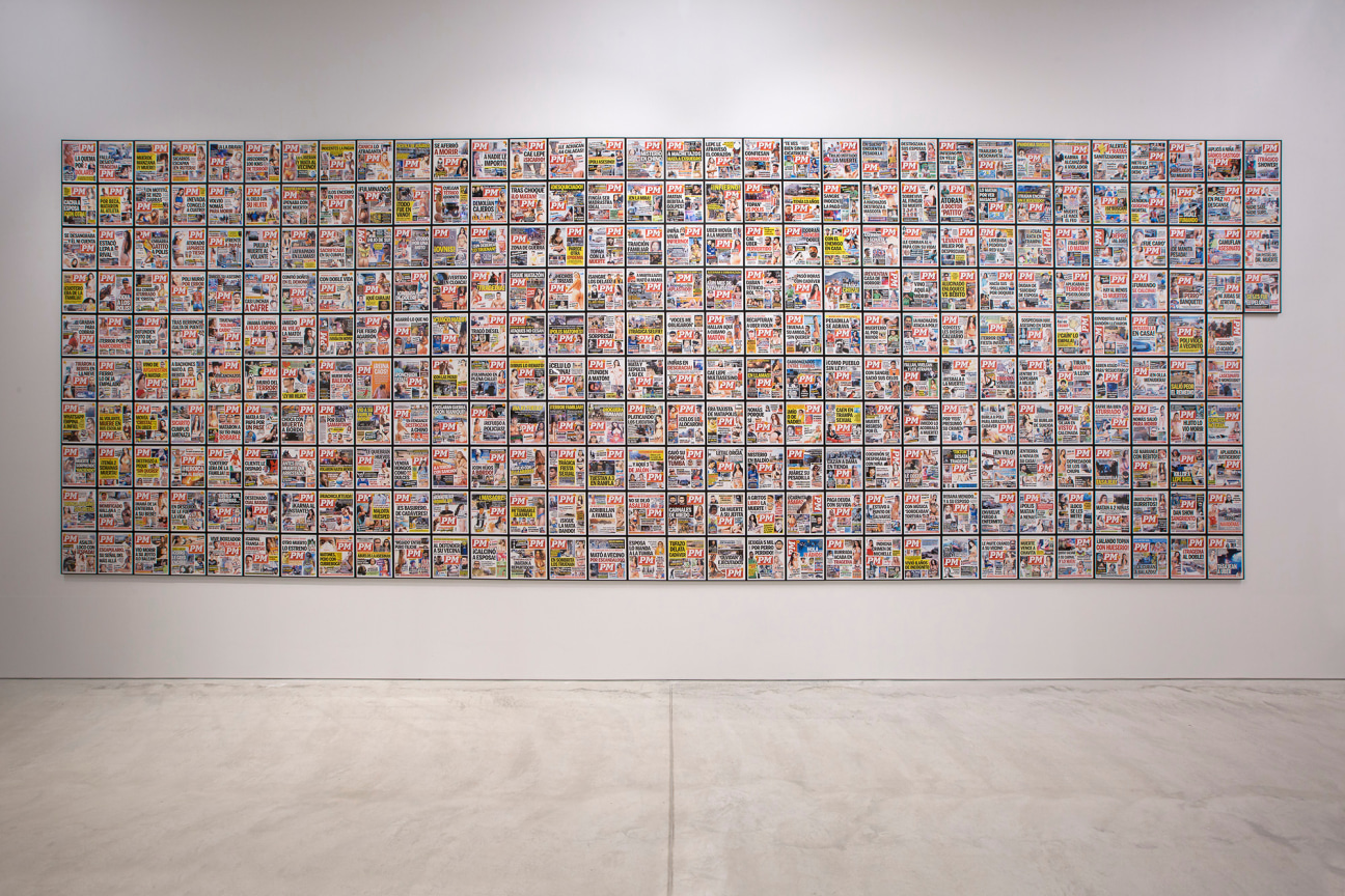 Print reproductions of newspaper mounted on wall in a grid-like arrangement