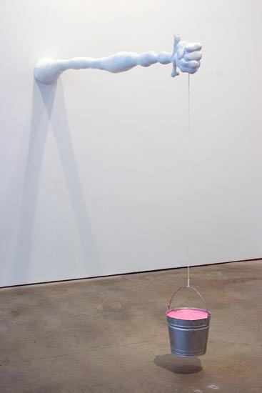 weird skinny arm extending from the wall while holding a bucket from a string