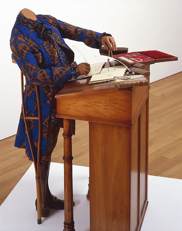 mannequin on a crutch and wearing a blue jacket using a compass