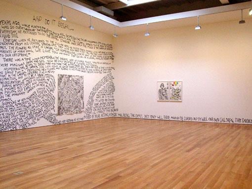 one wall is covered in words while the other is nearly blank, with only two paintings and a line of words at the bottom