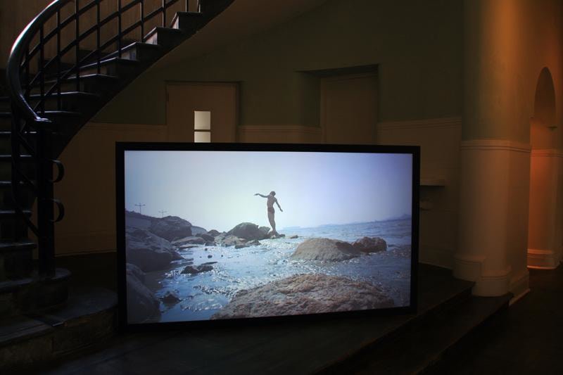 Image of video still of a man in a swimsuit at the beach
