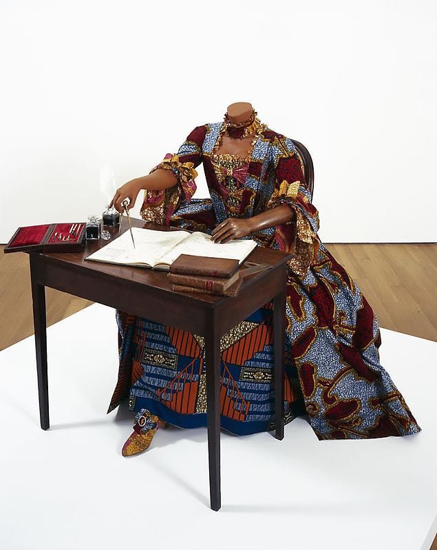 headless mannequin sitting at a desk and writing