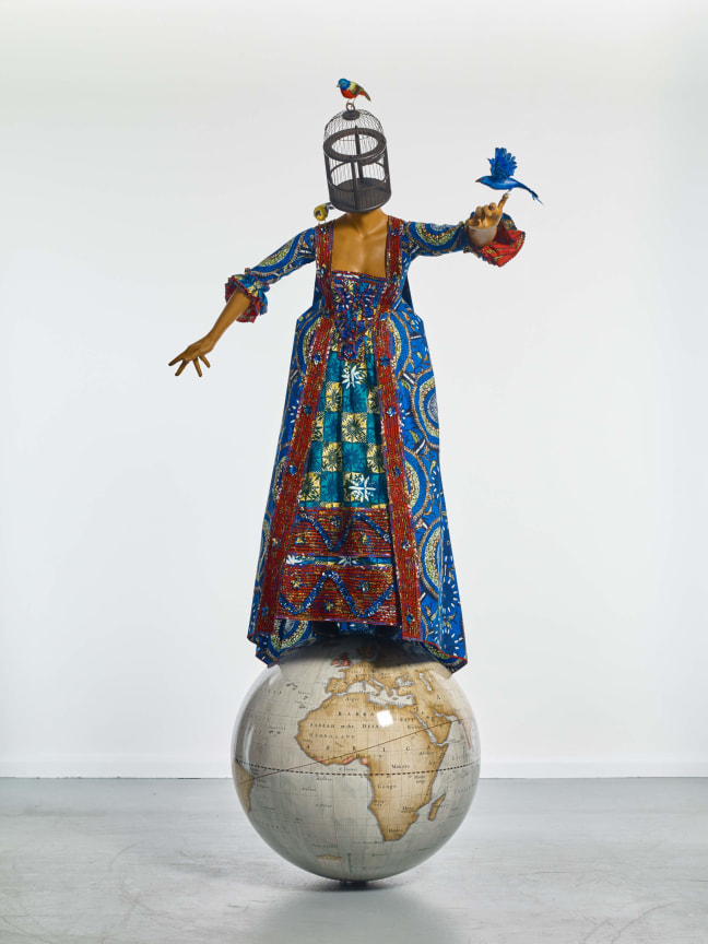 statue of a woman standing on a large globe with a birdcage for a head