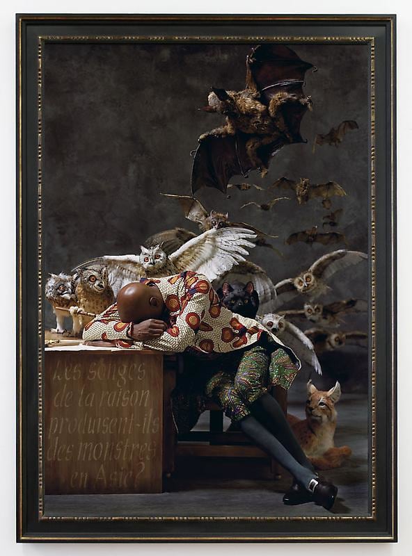 man fallen asleep at his desk with owls and bats emerging from behind