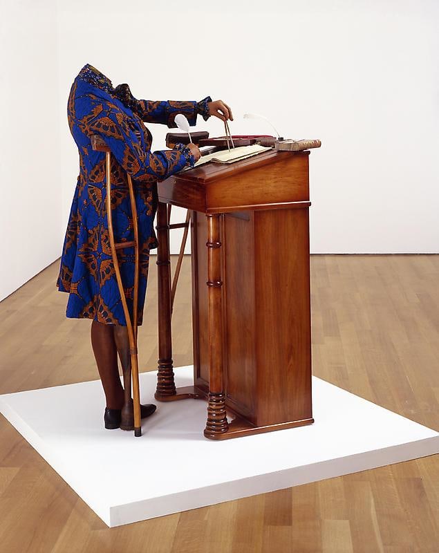 mannequin on a crutch and wearing a blue jacket using a compass