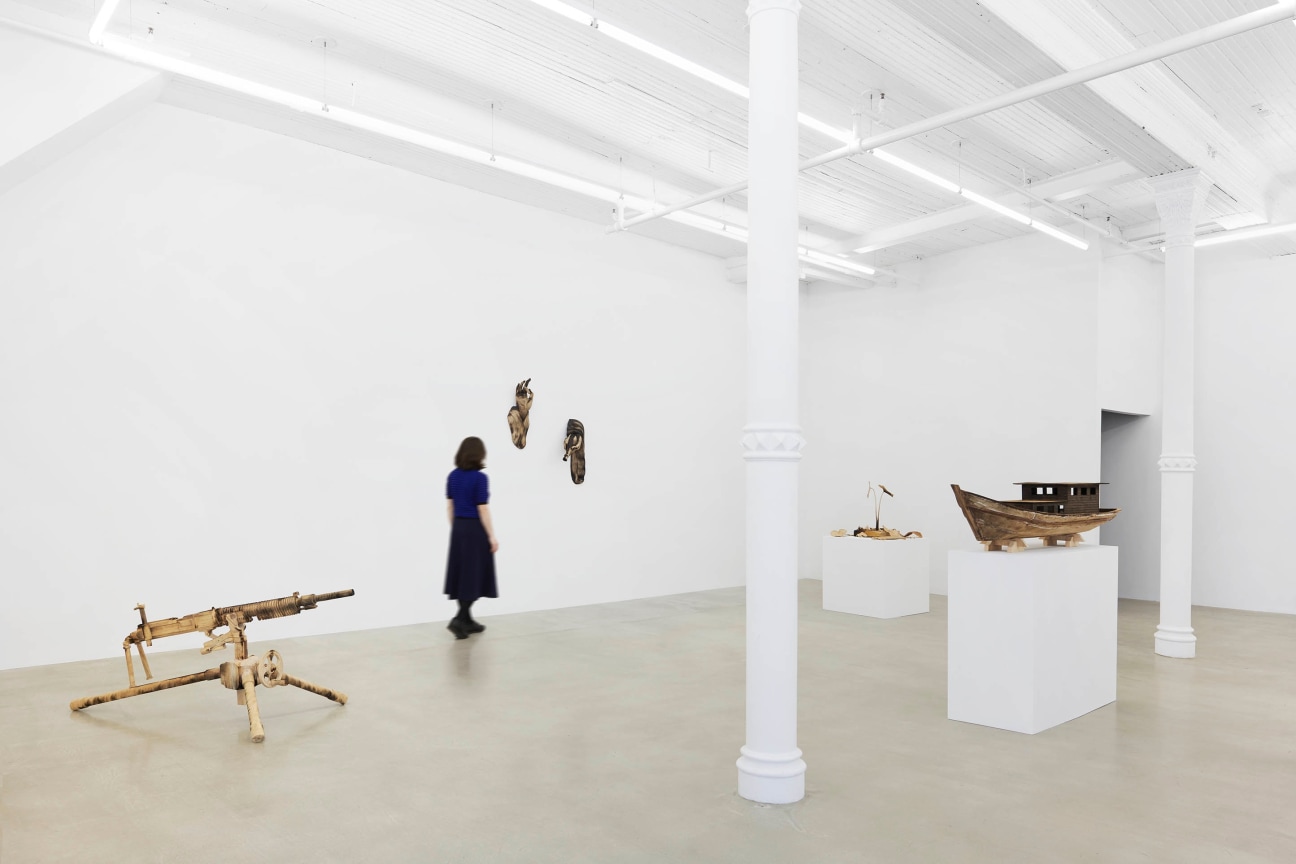 a woman walking amongst four wooden sculptures
