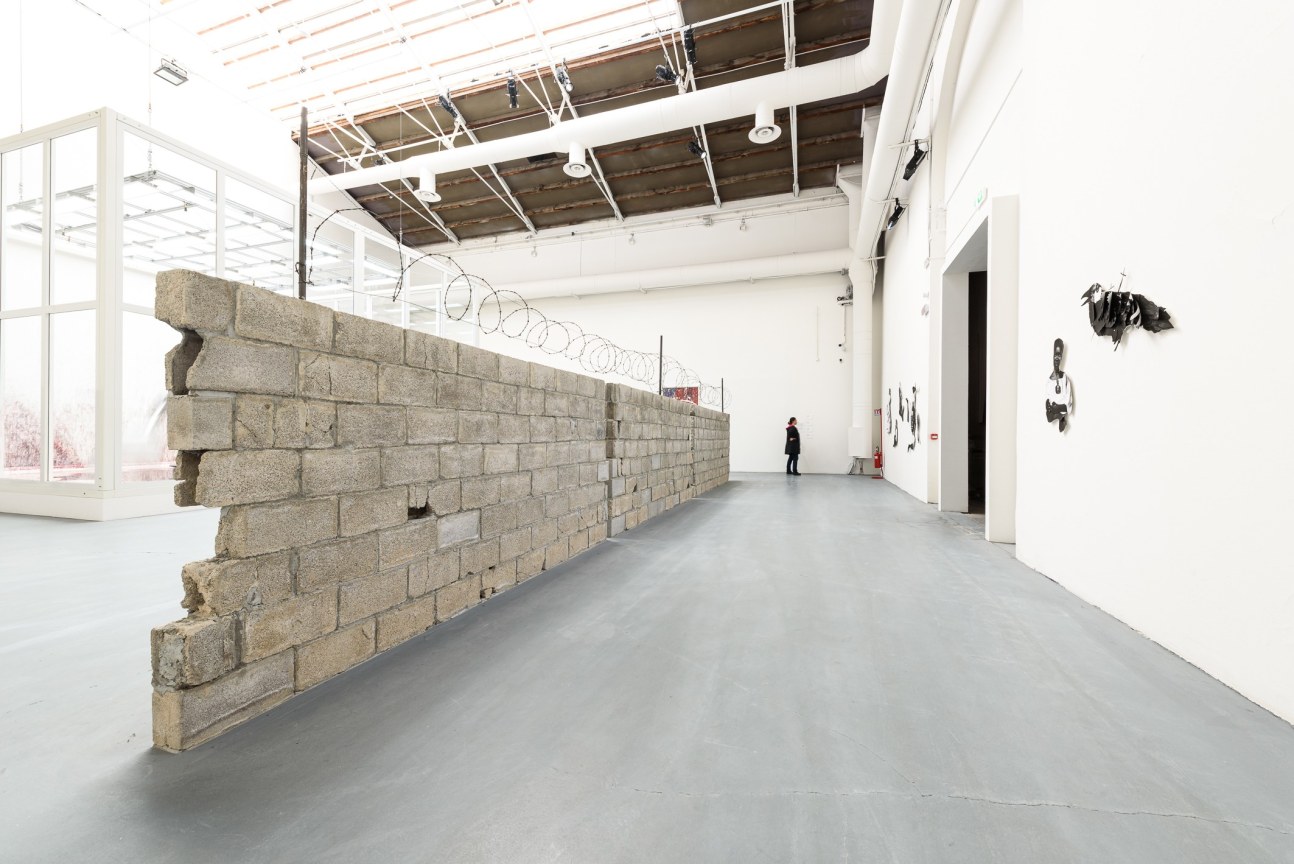 Side view of the wall of concrete blocks with barbed wire on top in exhibition hall