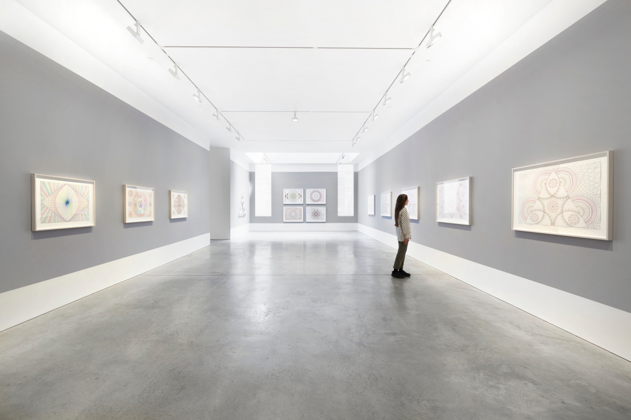 person looking at one of several drawings within a long gallery