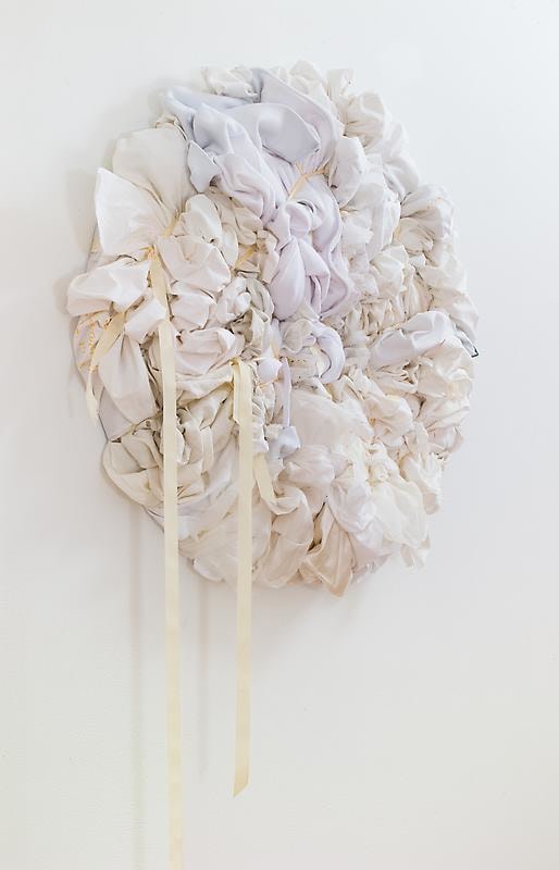 white bundles of cloth formed into a circle hanging from the wall