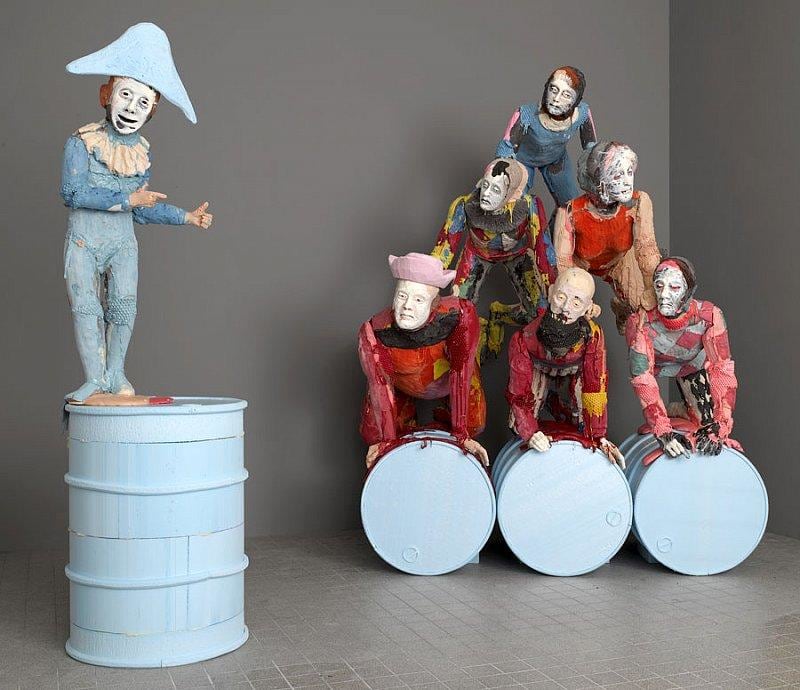 statues forming a human pyramid with a smaller statue pointing at them