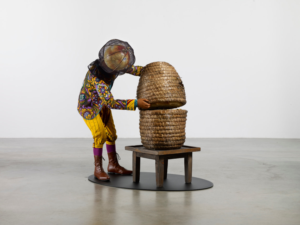 man with a globe for a head opening a beehive made of straw