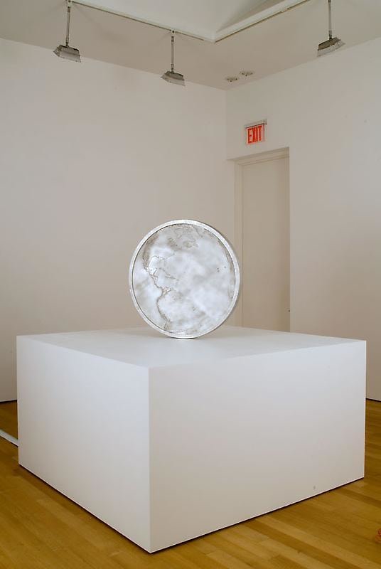 A large aluminum sculpture that resembles a coin.