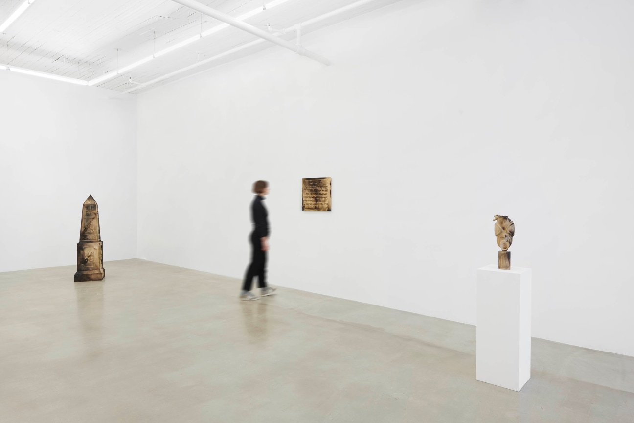 person walking in between three wooden sculptures