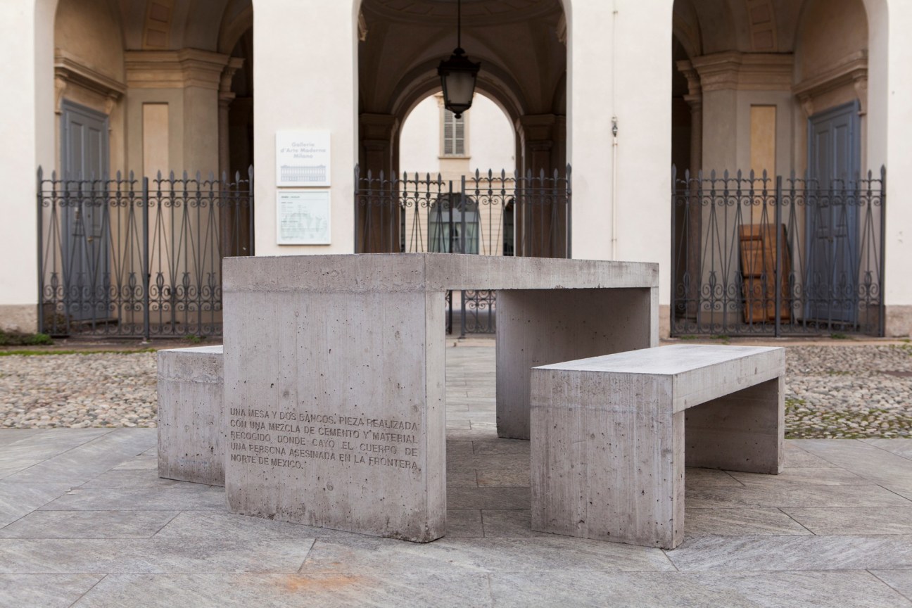 two benches and a table made out of cement; the table has an inscription on the side