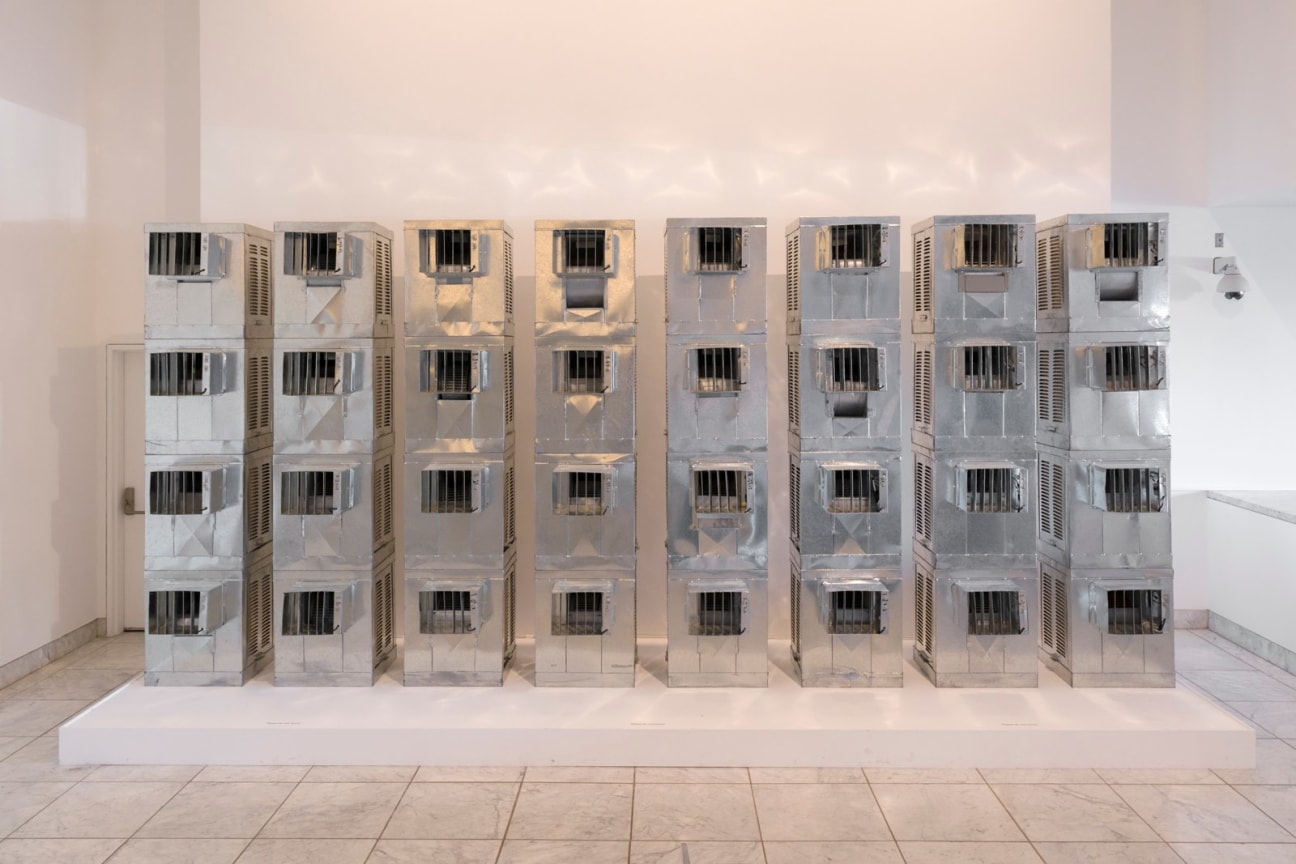 Thirty two air conditioning units stacked into eight columns on a white platform