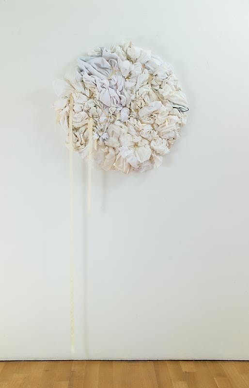 white bundles of cloth formed into a circle hanging from the wall