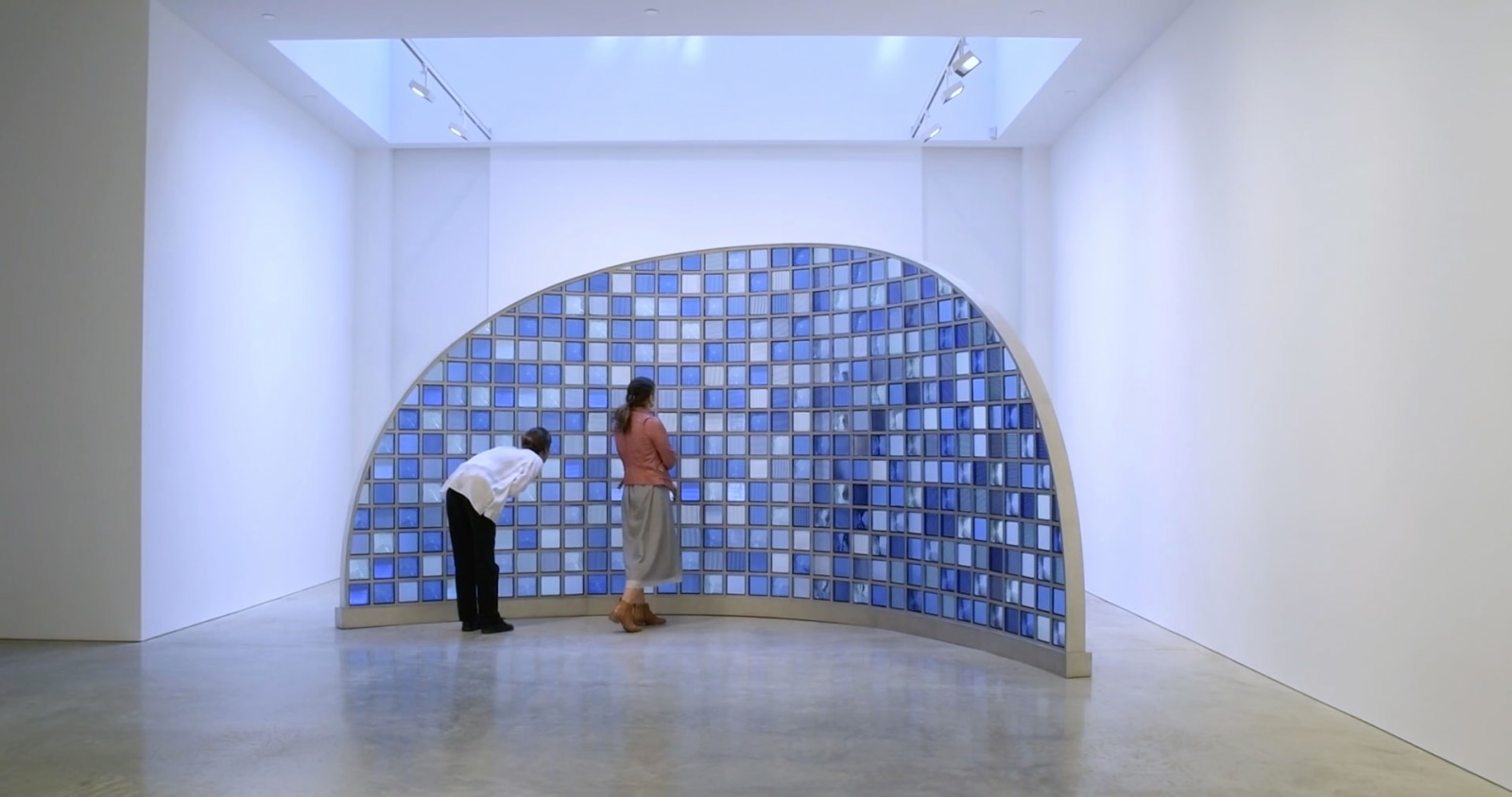 Curved moon-shaped sculpture under skylight in gallery space