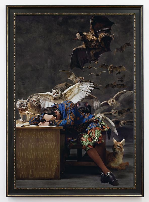 man fallen asleep at his desk with owls and bats emerging from behind