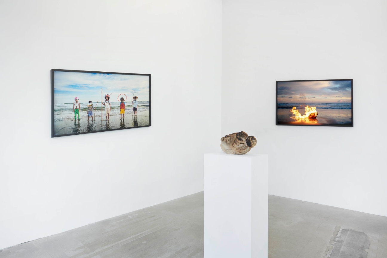 view of Tuan Andrew Nguyen's &quot;A Lotus in a Sea of Fire&quot; exhibition with two images and a sculpture in the middle