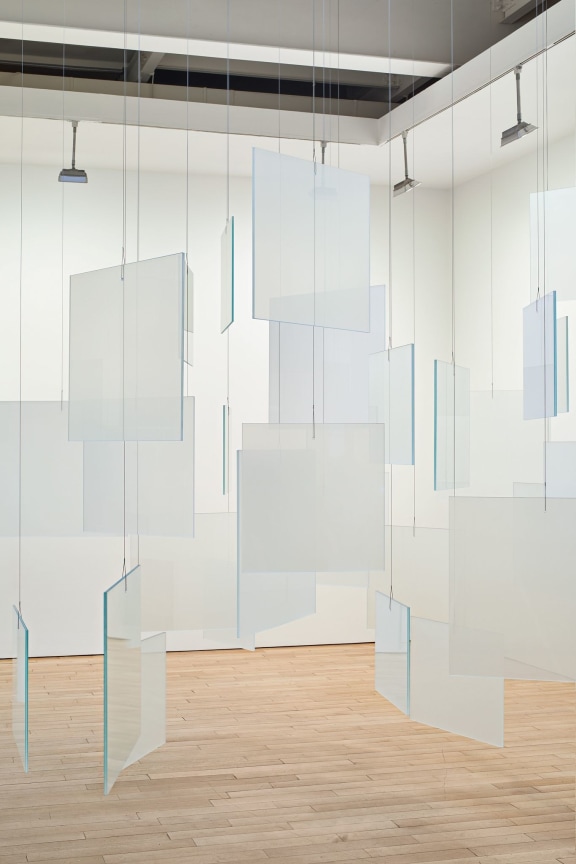 installation view of an artwork composed of glass panels hanging from the ceiling