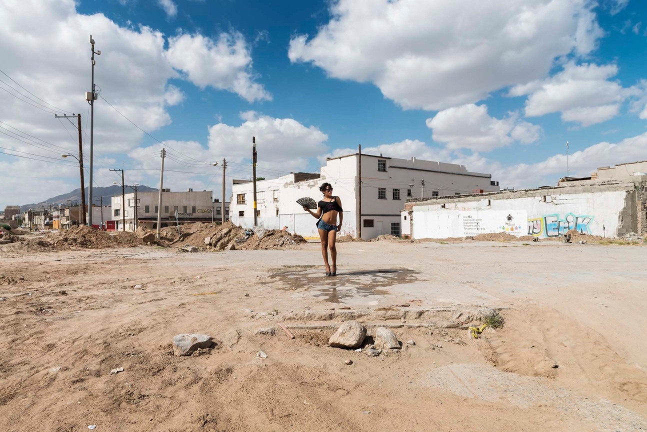 Club dancer holds a folding fan and poses in a deserted area