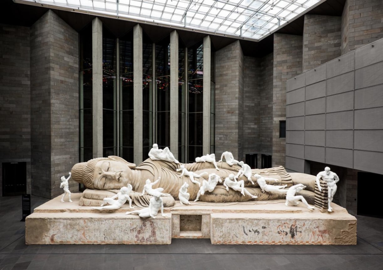 various Roamn-style sculptures laying on top of a giant Buddha