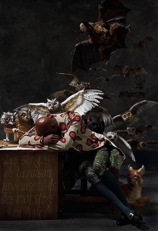 black man asleep on his desk with several animals behind him