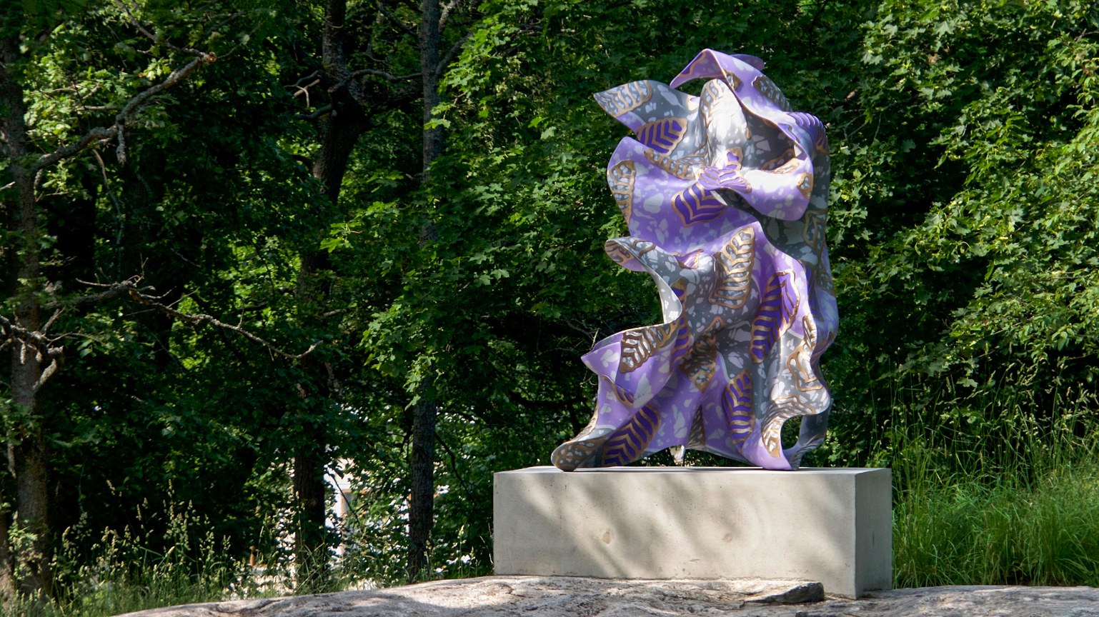 A large, purple, bronze, gestural sculpture sitting atop a rectangular base