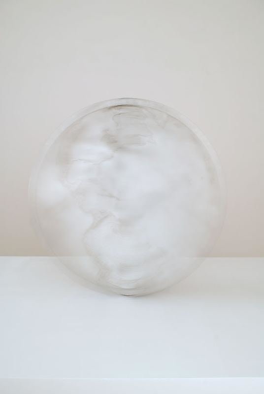 A large aluminum sculpture that resembles a coin in motion