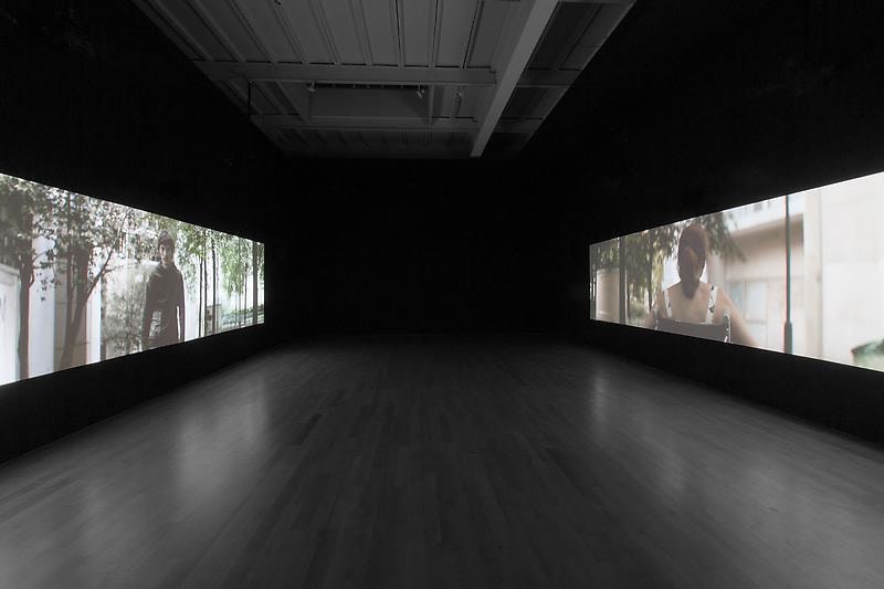 dark gallery with two video projections on opposite sides