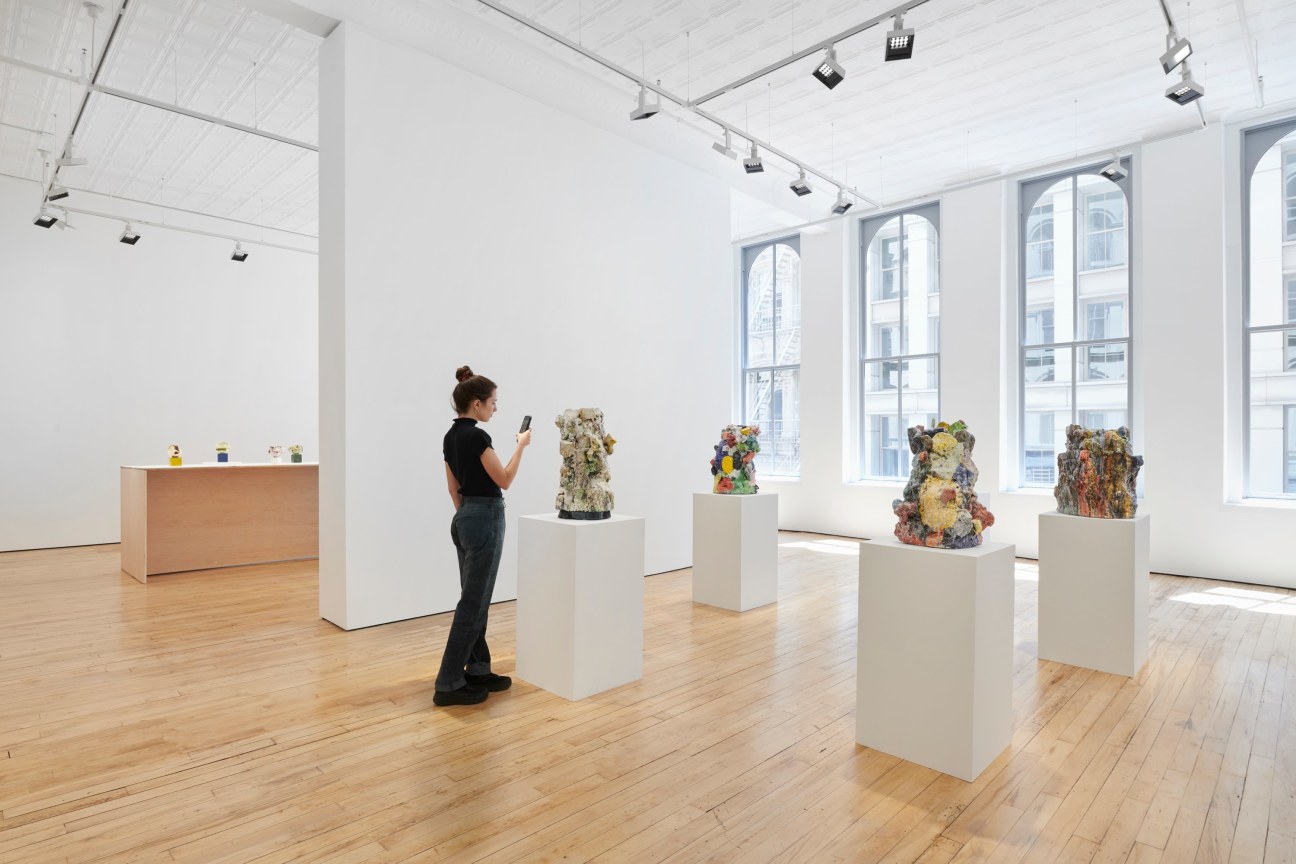 person taking a picture of sculptures on pedestals