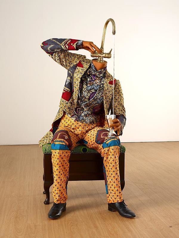 a mannequin with a faucet for a head pouring water in a cup