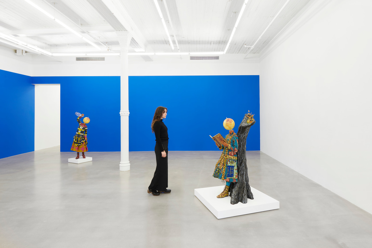 figure walking amongst two elaborately dressed mannequins