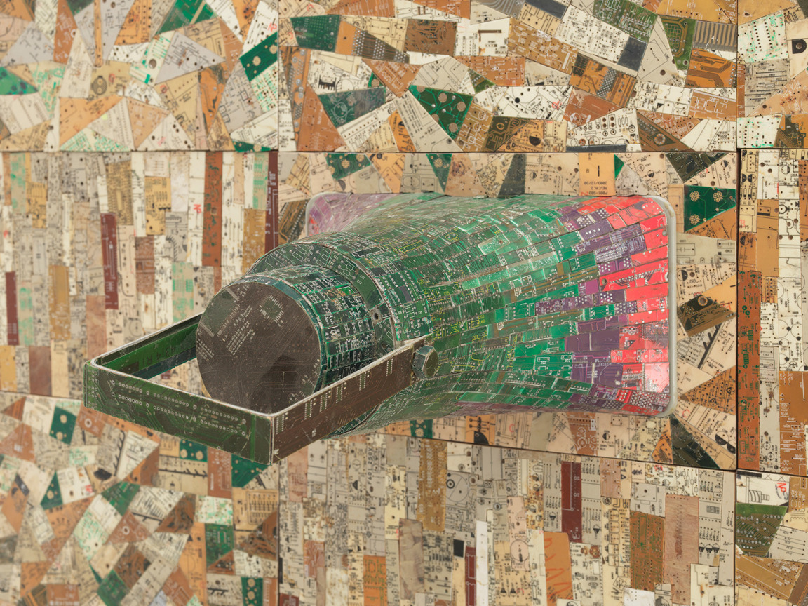 close up of a megaphone covered in electrical components emerging from a surface also composed of electrical components